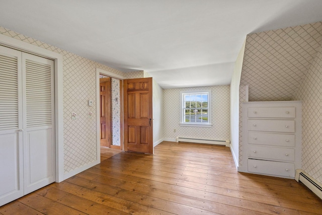 unfurnished bedroom featuring a baseboard radiator, light hardwood / wood-style flooring, and a closet