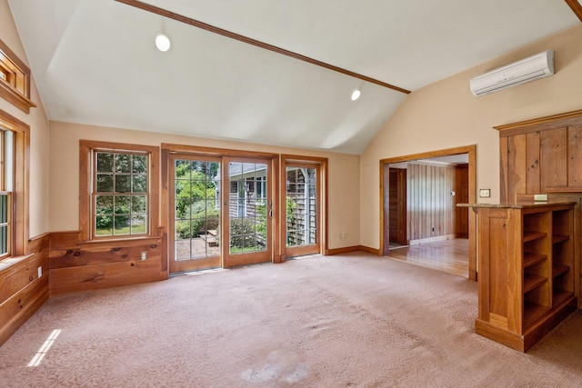 unfurnished living room featuring an AC wall unit, lofted ceiling, and light carpet