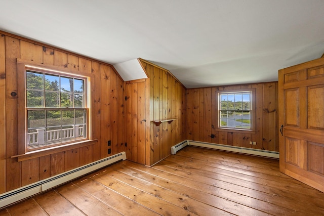 bonus room featuring light hardwood / wood-style floors, wooden walls, baseboard heating, and lofted ceiling