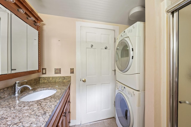 laundry area featuring sink, light tile patterned floors, and stacked washer and clothes dryer