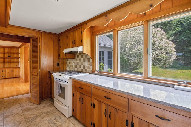 kitchen featuring light stone countertops, wooden walls, and white range with gas cooktop