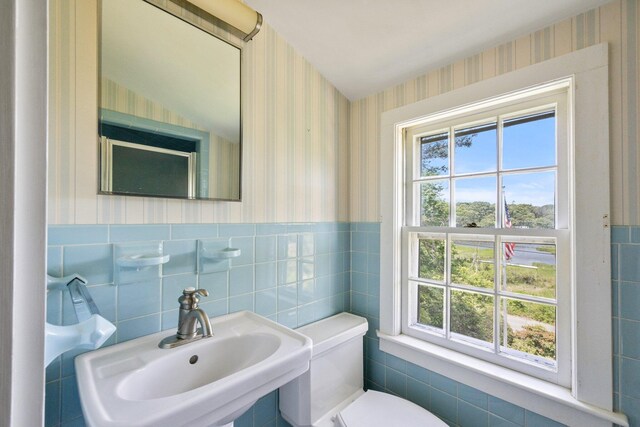 bathroom with sink, toilet, and tile walls