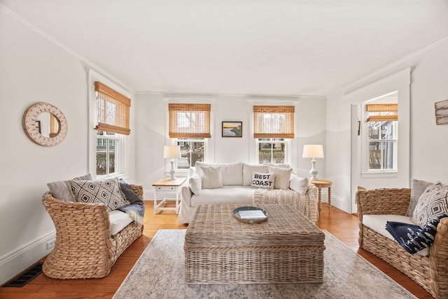 living room featuring hardwood / wood-style floors, crown molding, and a healthy amount of sunlight