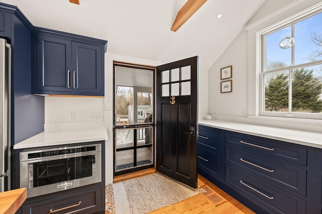 kitchen with blue cabinets, oven, light hardwood / wood-style floors, and lofted ceiling with beams