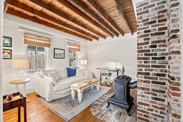 living room with beamed ceiling, wooden ceiling, light wood-type flooring, and a wood stove