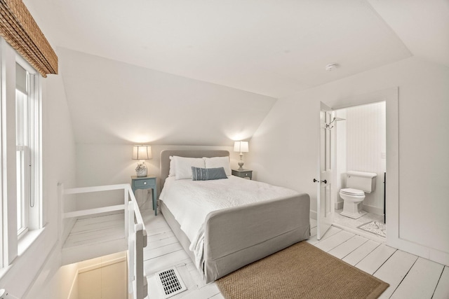 bedroom with lofted ceiling, ensuite bathroom, and multiple windows