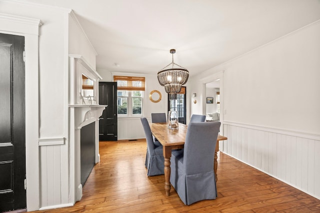 dining area with ornamental molding, a chandelier, and light hardwood / wood-style flooring