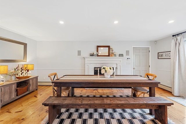 dining room with recessed lighting, light wood-type flooring, baseboard heating, and a fireplace