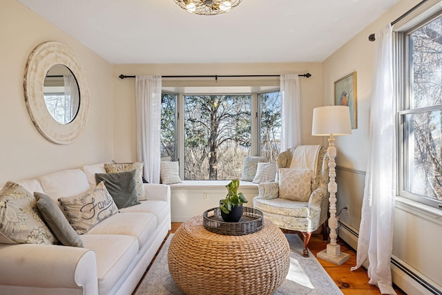 living area featuring plenty of natural light, baseboard heating, and wood finished floors