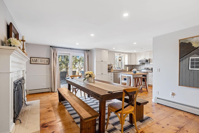 dining room with a baseboard heating unit, recessed lighting, light wood-style floors, and a fireplace