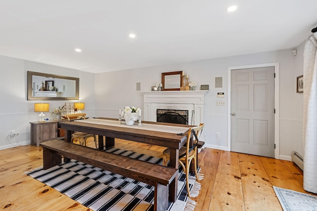 dining space with recessed lighting, a baseboard radiator, light wood-style flooring, and a fireplace