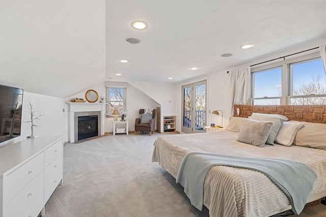 bedroom featuring vaulted ceiling, light colored carpet, and multiple windows