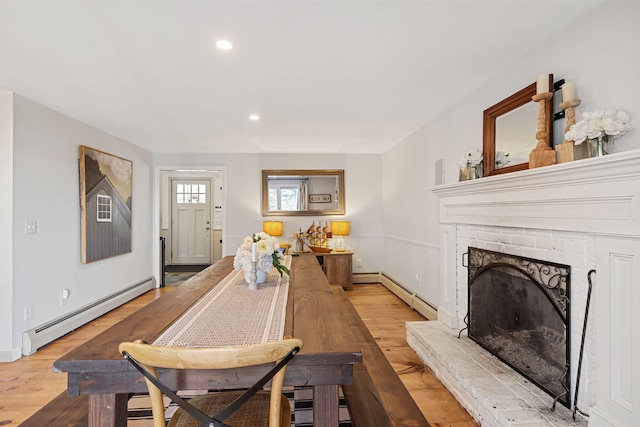 dining area with recessed lighting, a brick fireplace, wood finished floors, and a baseboard radiator