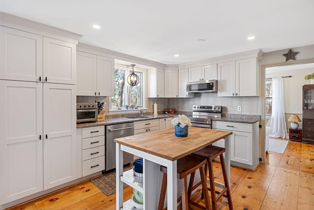 kitchen featuring a sink, tasteful backsplash, light wood-type flooring, and stainless steel appliances