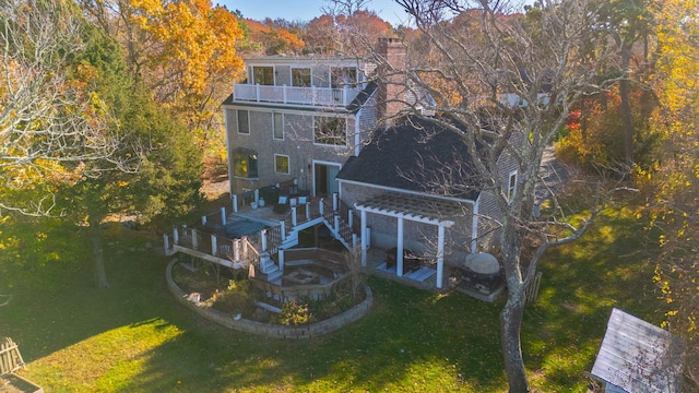 exterior space featuring a balcony, a chimney, and a yard