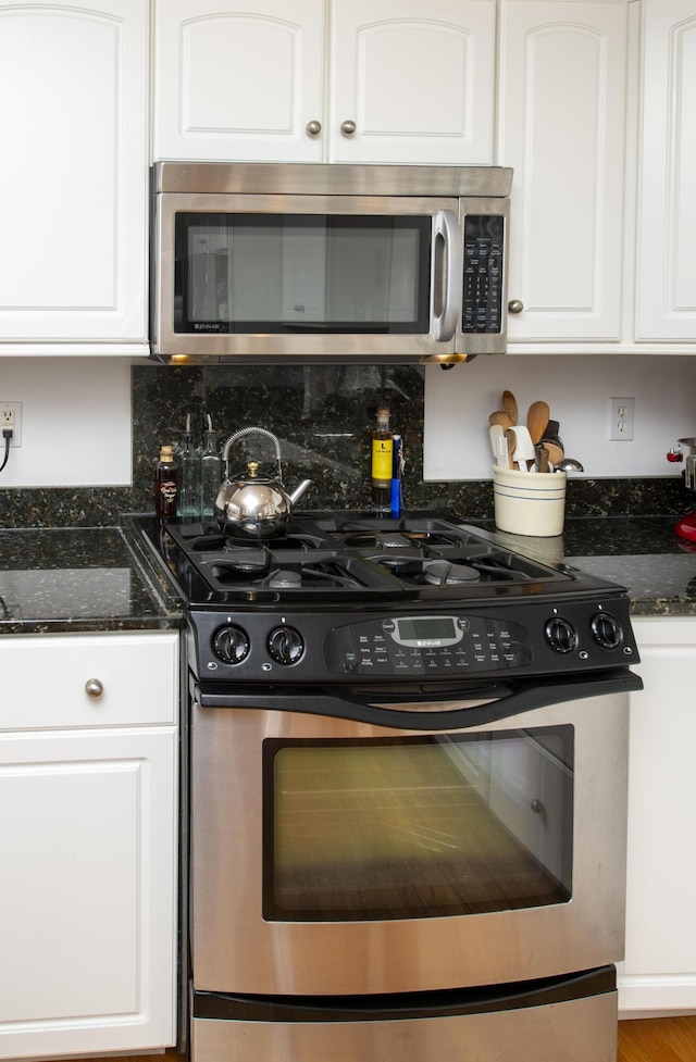 2181 Service Rd, West Barnstable, MA 02668 - kitchen with stainless steel appliances, white cabinets, dark stone counters, and decorative backsplash