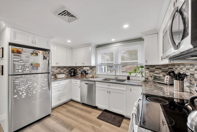 kitchen with visible vents, stone counters, a sink, stainless steel appliances, and white cabinetry