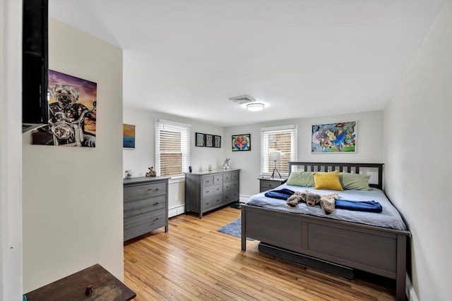 bedroom with visible vents, multiple windows, light wood-style floors, and a baseboard radiator