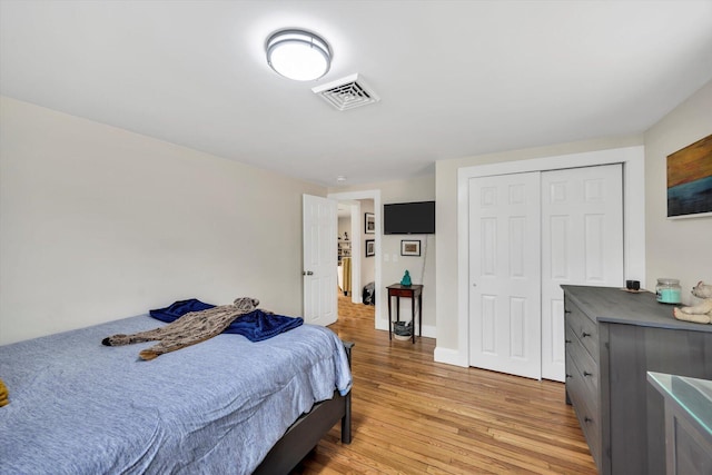 bedroom featuring a closet, visible vents, light wood-type flooring, and baseboards