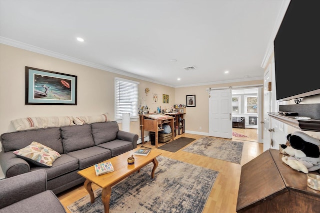 living area featuring light wood finished floors, visible vents, crown molding, and a barn door