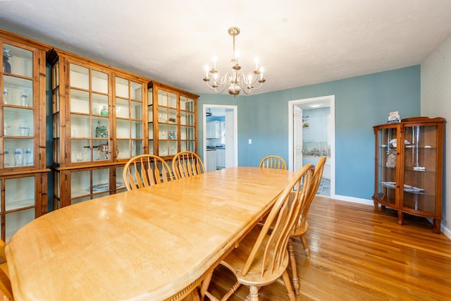 dining space with a notable chandelier, wood finished floors, and baseboards