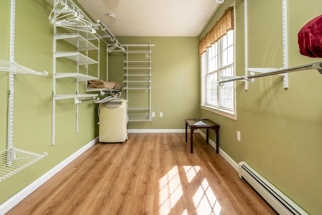 spacious closet with wood finished floors and a baseboard radiator