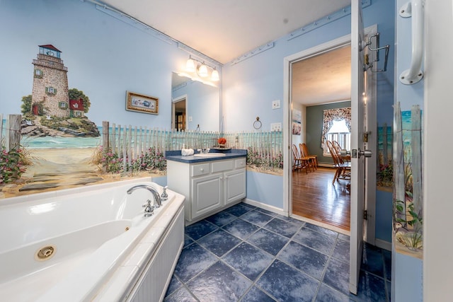 bathroom featuring vanity, baseboards, a whirlpool tub, and stone finish flooring