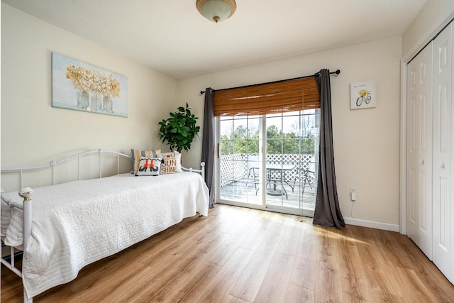 bedroom with a closet, baseboards, wood finished floors, and access to outside