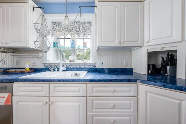 kitchen featuring dark countertops, white cabinetry, and a sink