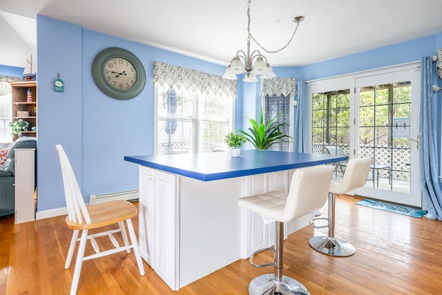 dining room with a baseboard radiator, an inviting chandelier, and light wood finished floors