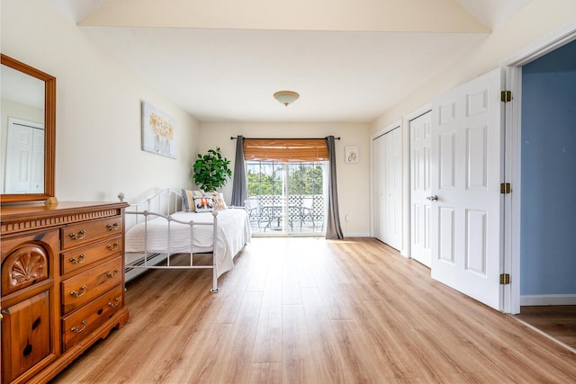 bedroom with access to exterior, light wood finished floors, baseboards, multiple closets, and baseboard heating