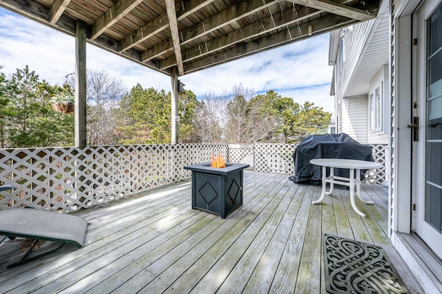 wooden deck with grilling area and an outdoor fire pit