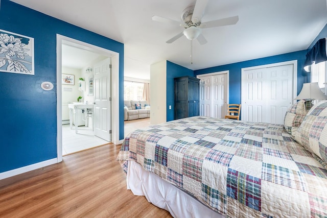 bedroom with wood finished floors, baseboards, ceiling fan, multiple closets, and baseboard heating