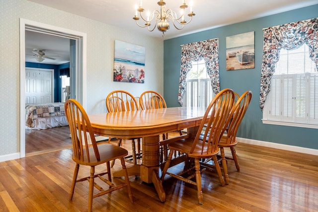 dining room with wallpapered walls, a notable chandelier, wood finished floors, and baseboards