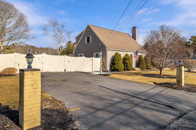 view of side of home featuring a gate, fence, and a chimney