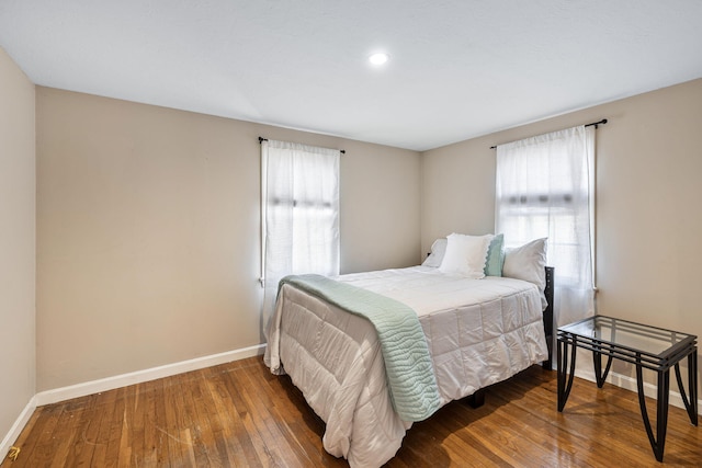 bedroom featuring hardwood / wood-style flooring, multiple windows, and baseboards