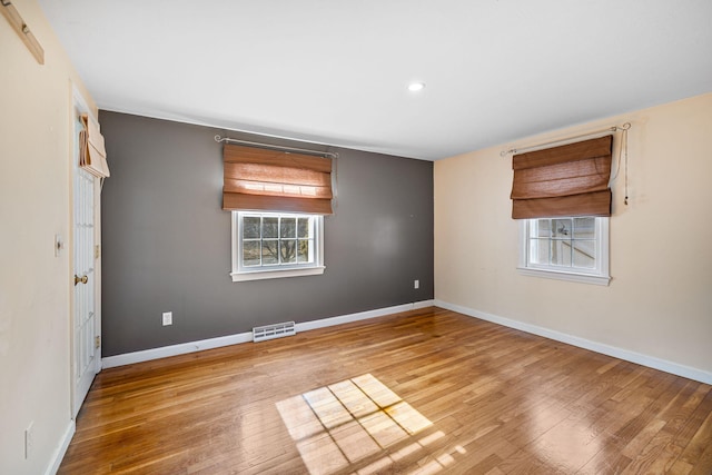 empty room with visible vents, baseboards, and wood finished floors