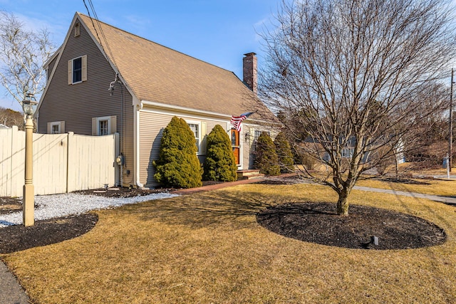 view of side of home with a chimney, fence, and a yard