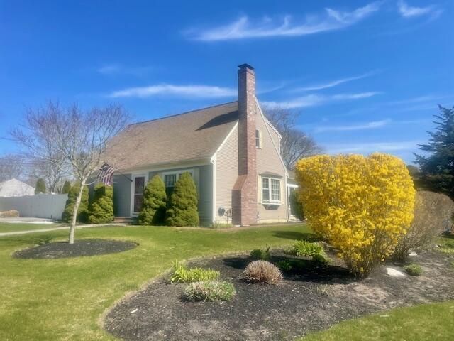 view of side of home with a yard and a chimney