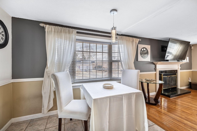 dining space with wood finished floors, a high end fireplace, and baseboards