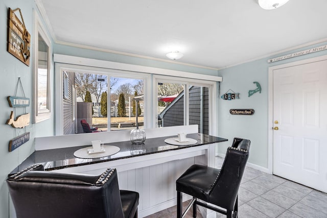 dining space with ornamental molding, light tile patterned flooring, and baseboards