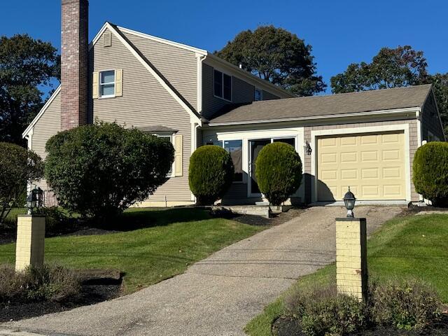 view of front facade featuring a garage, a chimney, driveway, and a front yard