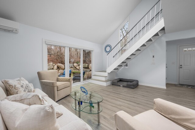 living room with vaulted ceiling, stairway, wood finished floors, baseboards, and an AC wall unit