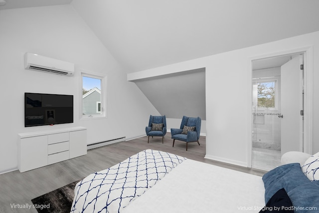 bedroom with ensuite bathroom, a baseboard radiator, wood finished floors, a wall unit AC, and vaulted ceiling