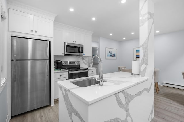 kitchen featuring white cabinets, light wood-style flooring, stainless steel appliances, recessed lighting, and a sink