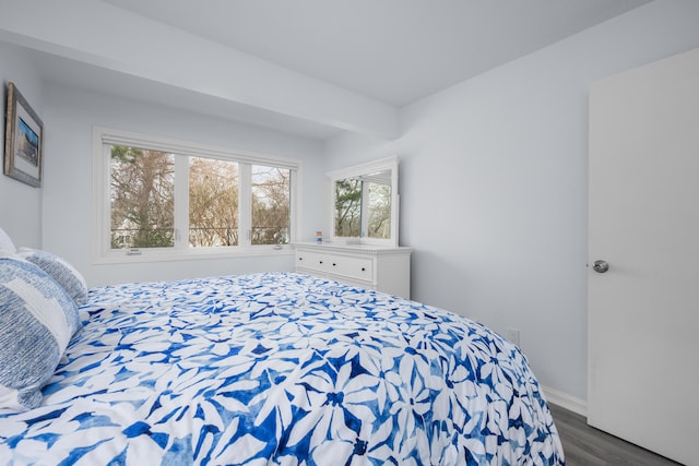 bedroom with dark wood-style floors, beamed ceiling, and baseboards