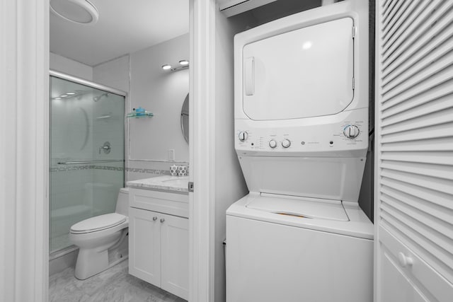 washroom featuring marble finish floor, stacked washer and clothes dryer, and laundry area