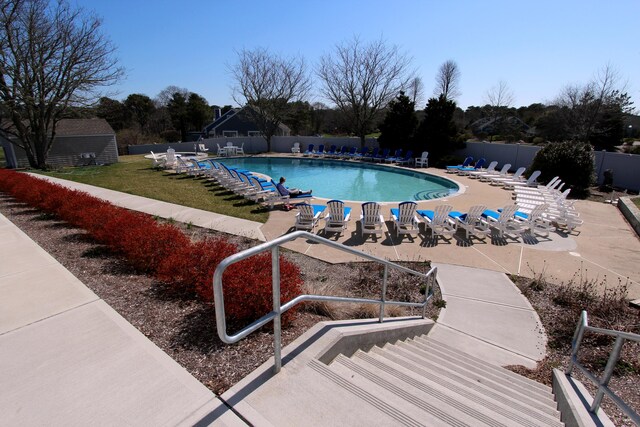 pool with a patio area, fence, and a yard