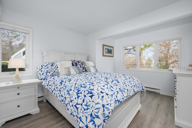 bedroom featuring baseboards, a baseboard heating unit, light wood-style floors, and a baseboard radiator