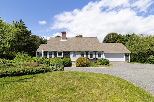 cape cod home featuring a front yard and a garage